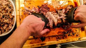 Shredding pulled pork with wolf claws to make BBQ Sandwich